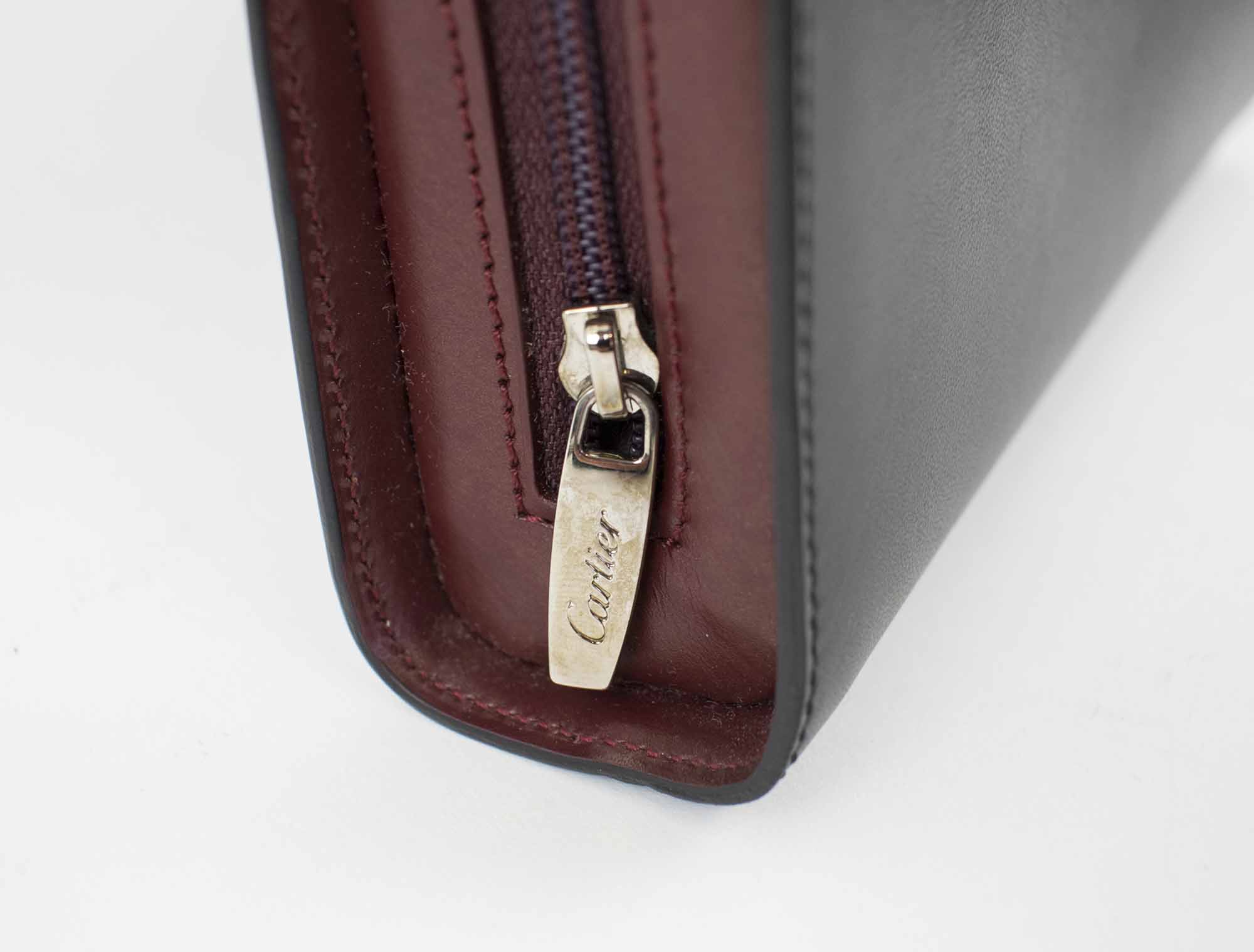 CARTIER MINI TRINITY CLUTCH/WALLET, black and burgundy leather with two top  handles, one silver tone and the other gold tone, single top zip, black  interior, 17cm x 11cm H x 4cm.