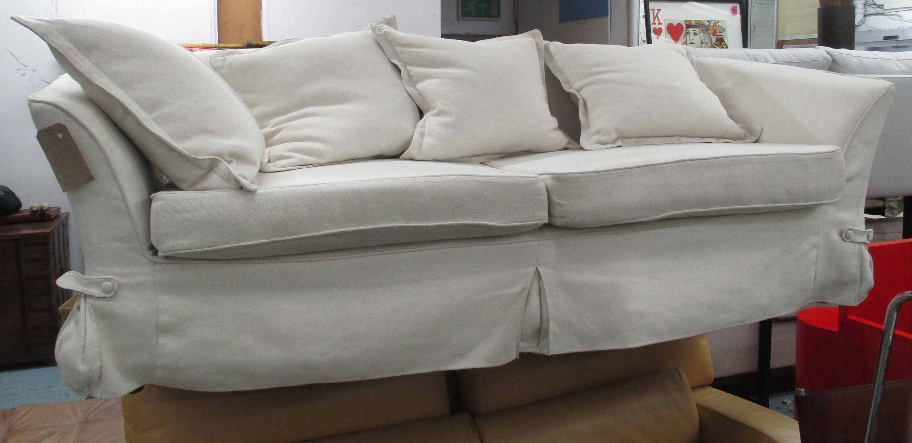 SOFA, two seater, in cream loose covers on turned supports, 220cm L.